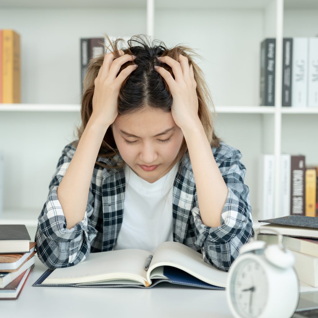 Frustrated student struggling to study Economics before tuition for Economics session.