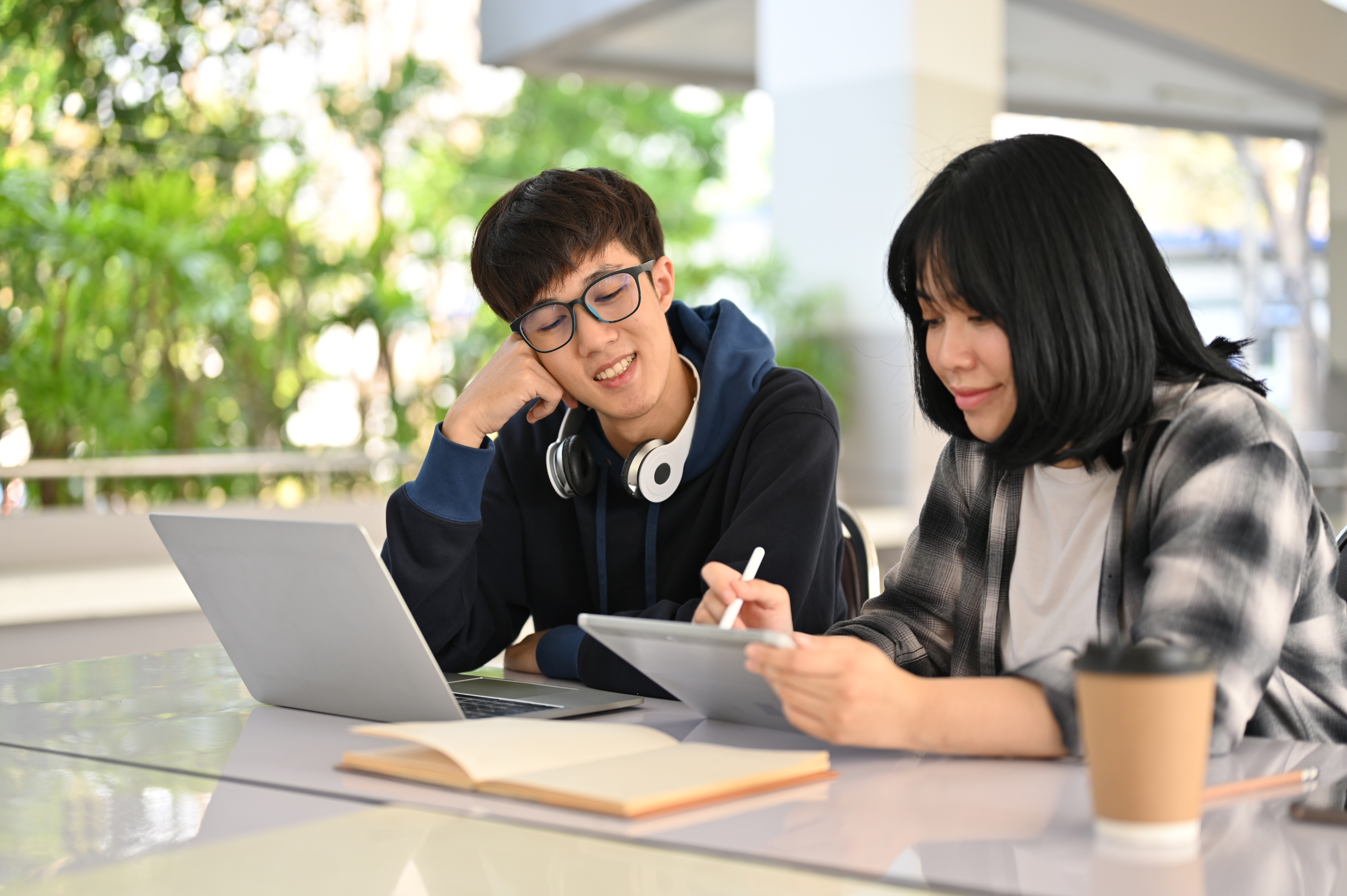 Students studying Economics together using a laptop and tablet during tuition for Economics.